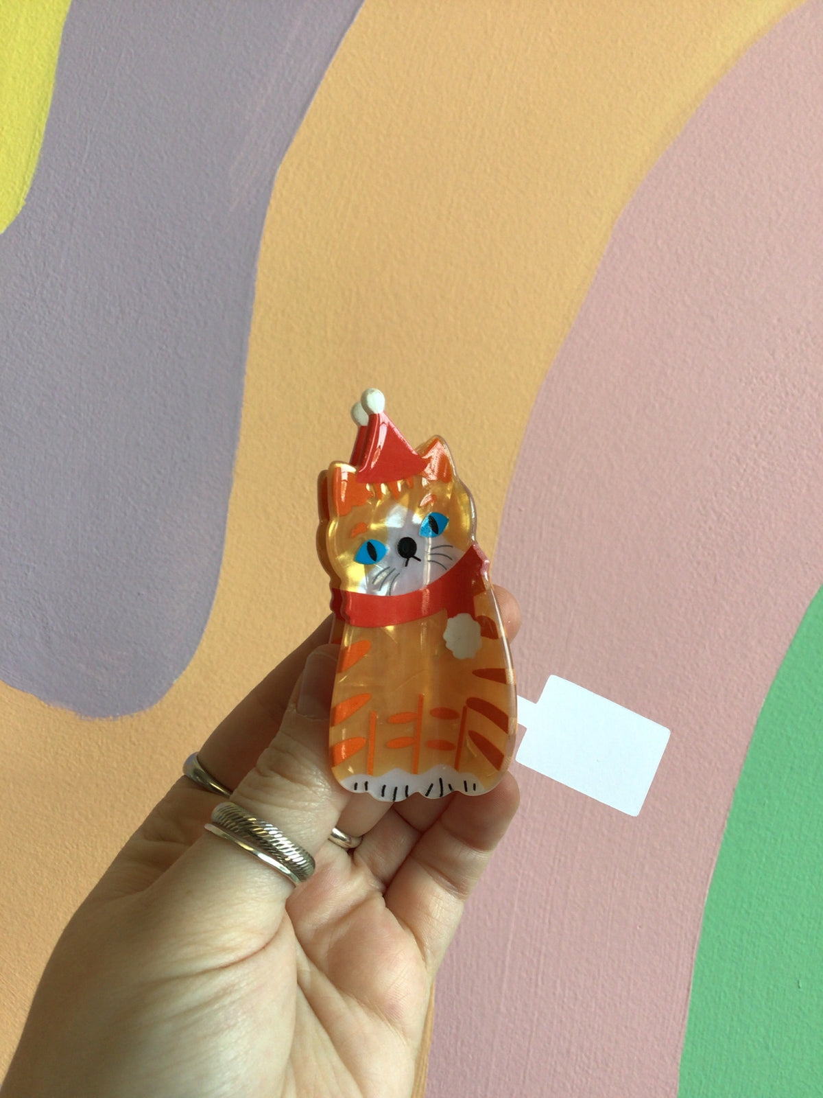 Festive cat hair claw with orange cat figure and red cone-like headpiece