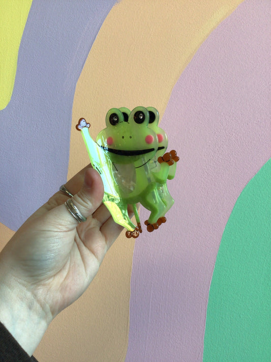 Green frog hair claw with big eyes, tiny smile, and clear glittery body.