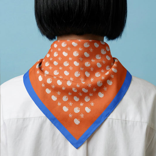 Orange cotton bandana around neck with blue edge and white tiny fruit print.