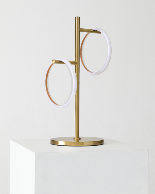 Gold Saturn table lamp with two white glowing circular rings on a round base.