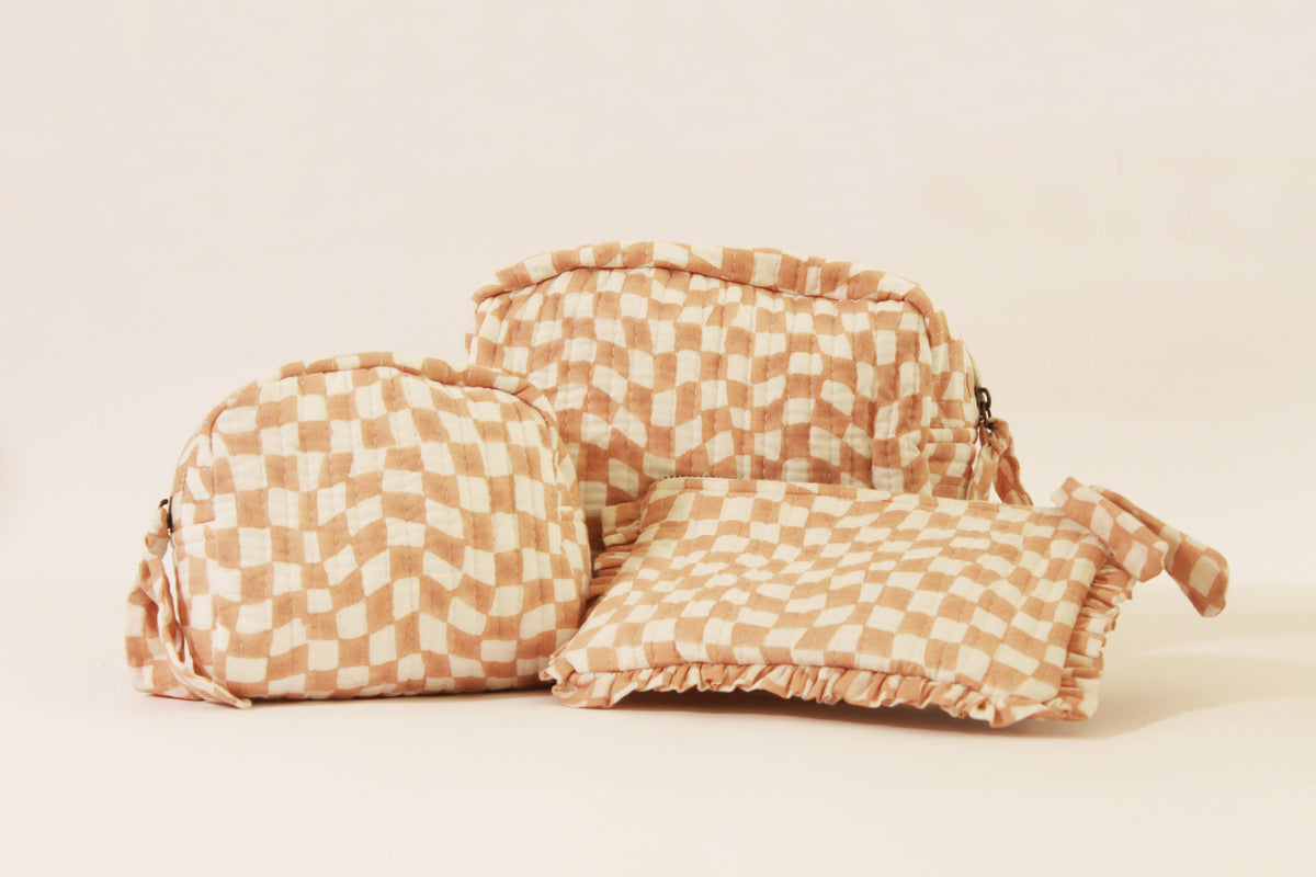 Handmade quilted pouch with flap, peach-and-white checkered fabric, gathered top and tassel.