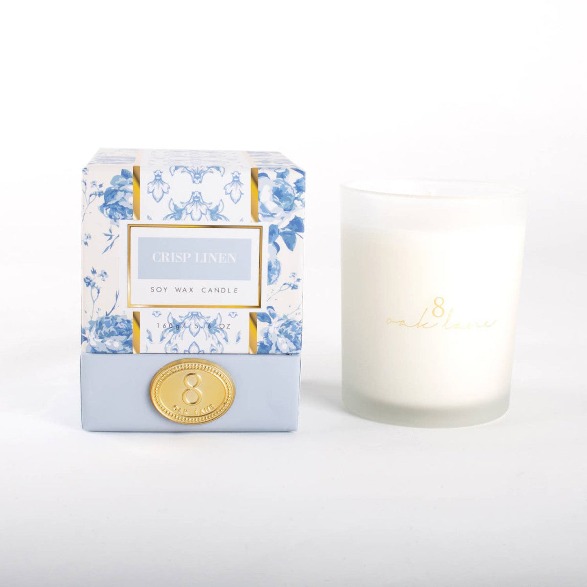 Boxed soy wax candle with white glass jar, blue floral print label and gold seal
