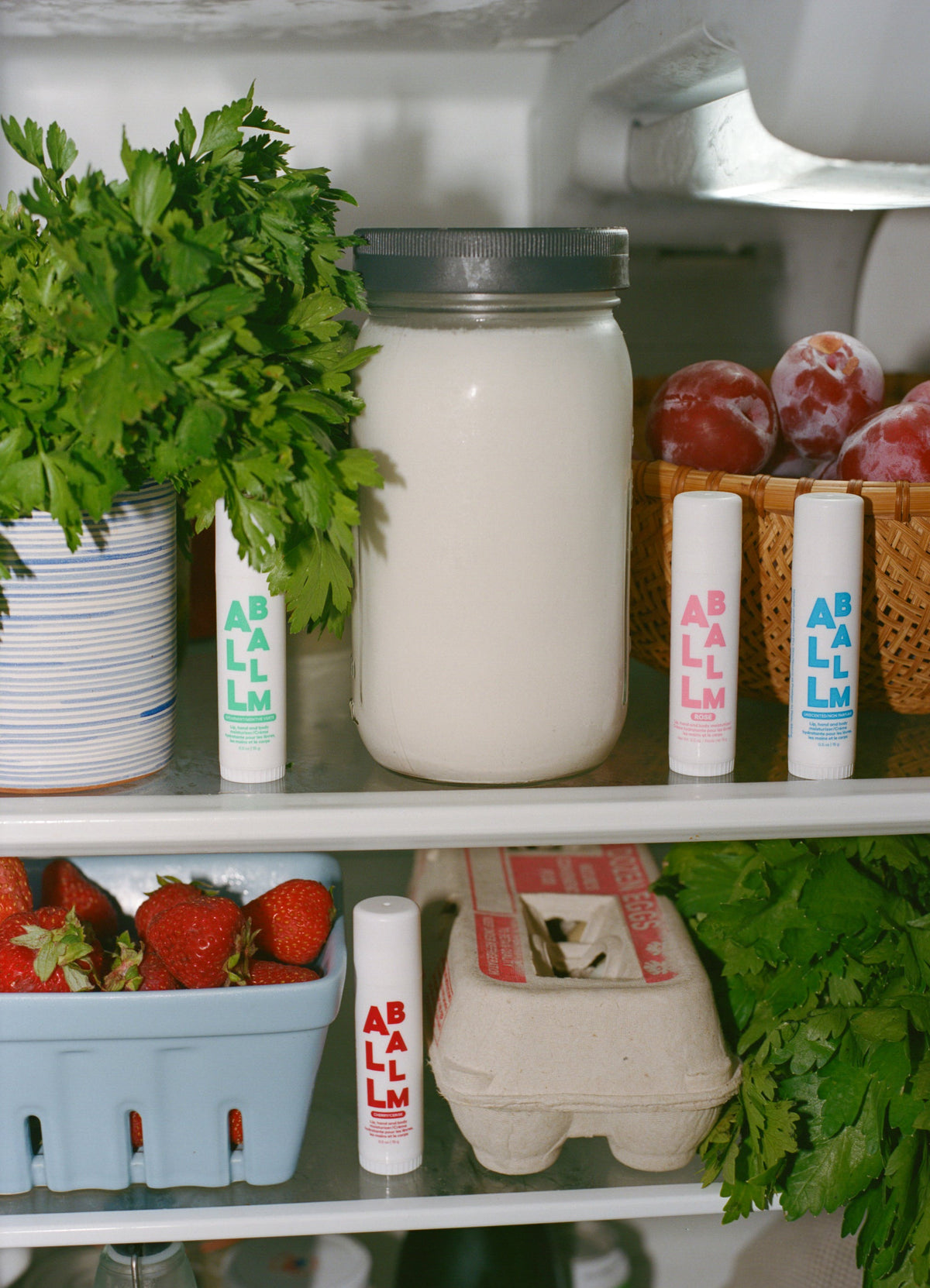 Balm stick tubes standing on a shelf with white and colored ABALM labels