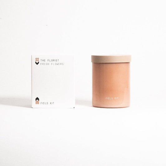 Florist candle with amber jar and tan lid beside 'FIELD KIT' box
