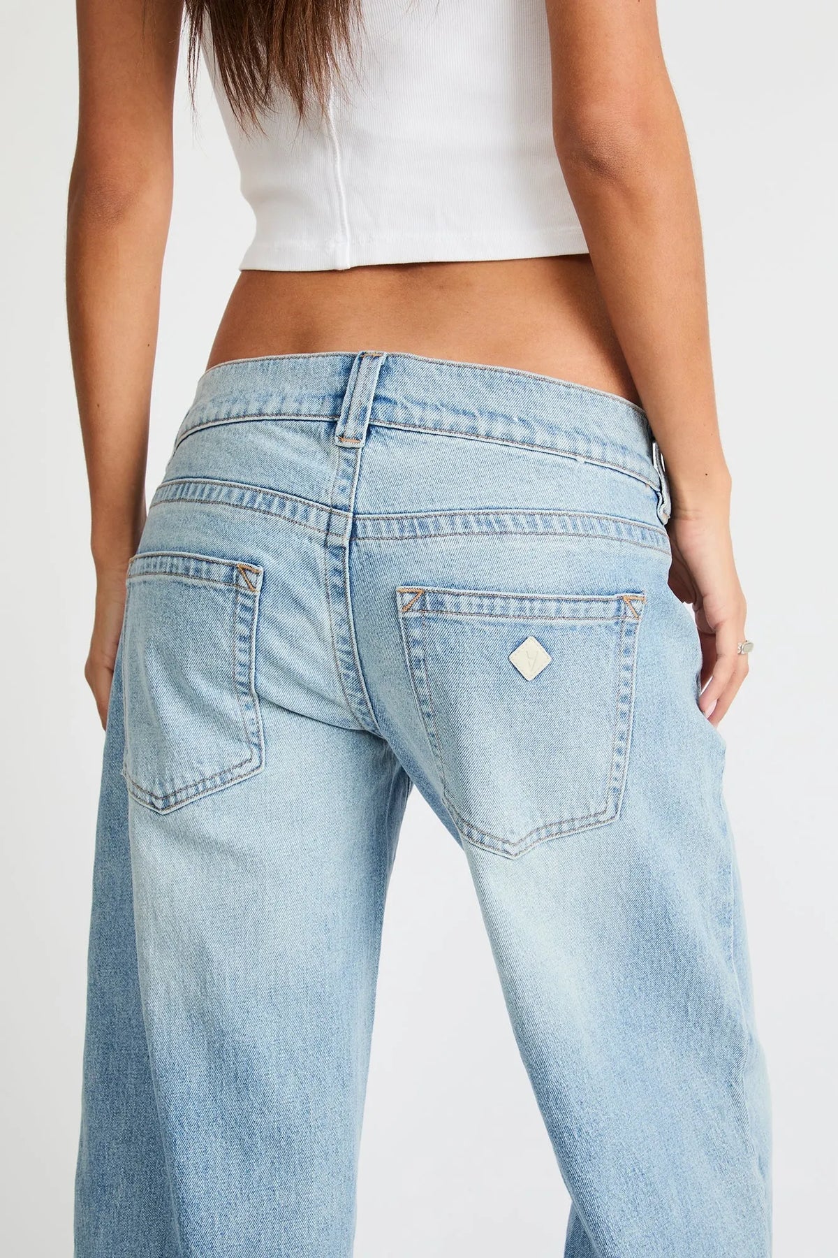 Light blue denim jeans close-up: back pockets, belt loops, metal diamond patch