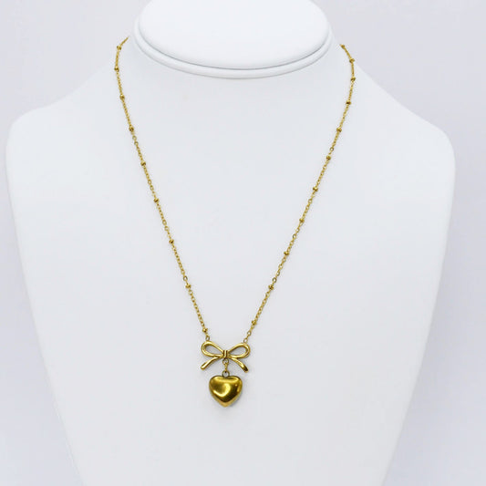 Gold bow and heart pendant necklace displayed on a mannequin
