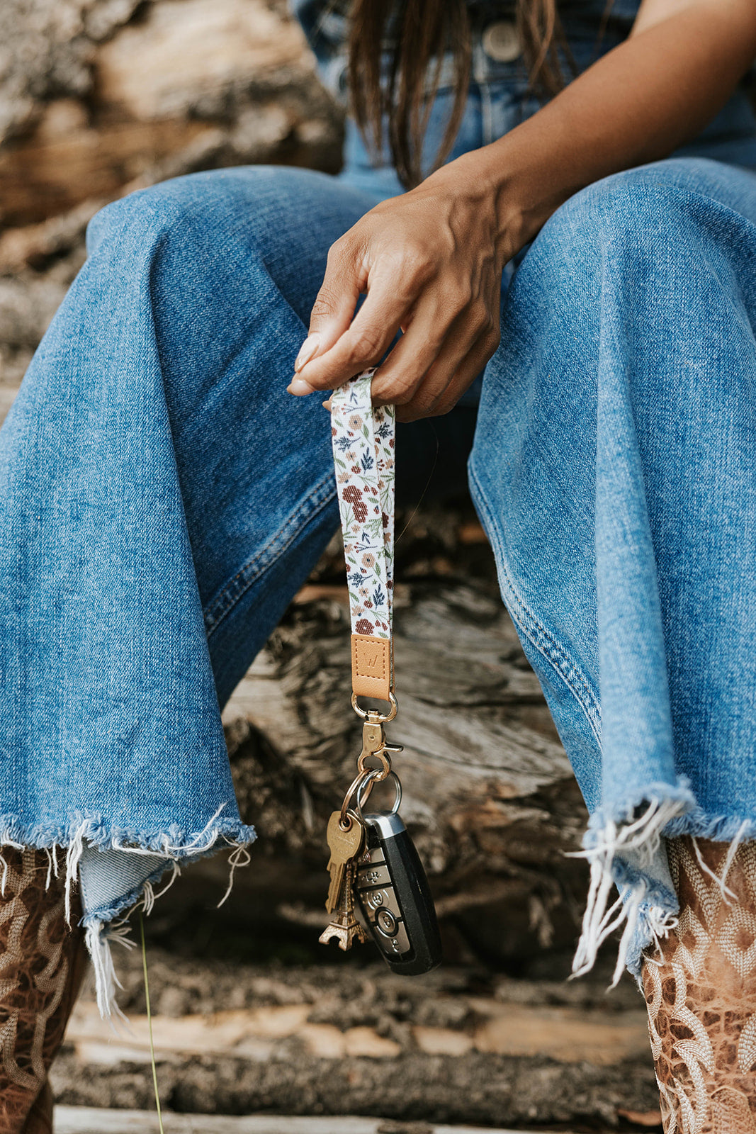 Floral wrist lanyard with tan leather, metal clip, and dangling phone charm