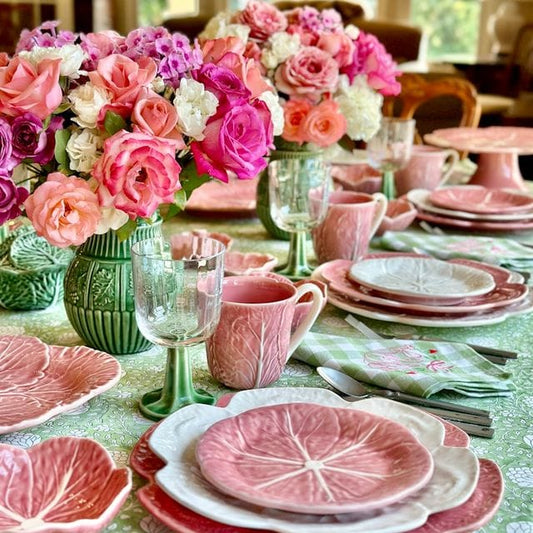Pink cabbage-pattern ceramic mugs with white handles and rims in dining table setting.