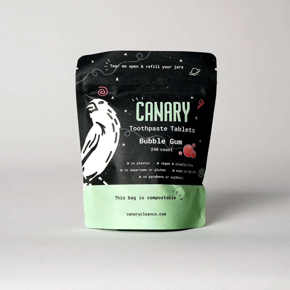 Bubble gum toothpaste tablets in a resealable black and mint-green pouch with a parrot graphic