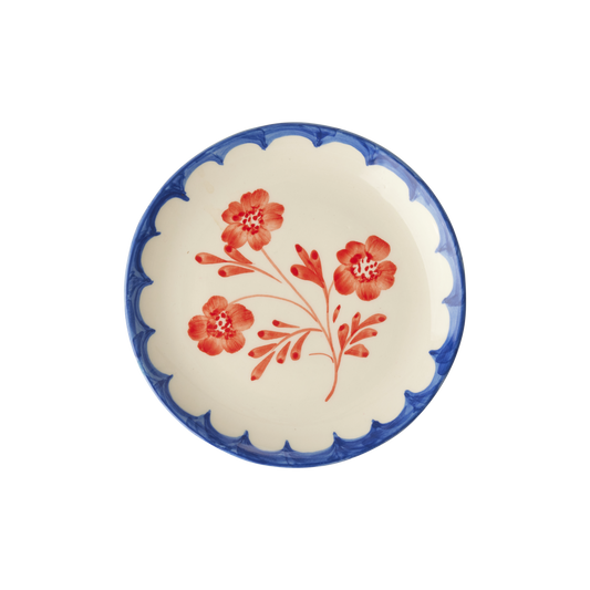 Round ceramic cake plate with scalloped blue rim and red vintage flower on white glaze