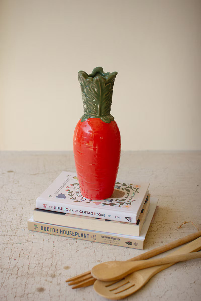 Orange ceramic carrot vase with glossy orange finish and dark green leaves