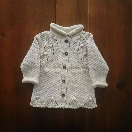 Ecru textured knit cardigan with snap buttons, long sleeves, and scalloped edges