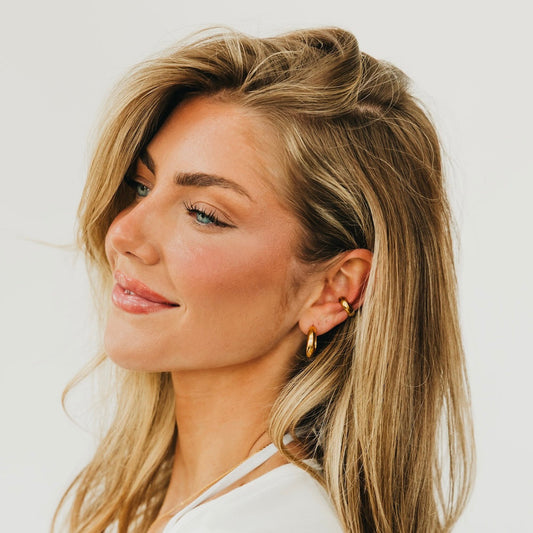 Gold conch ear cuffs and small hoop earrings, side view on model
