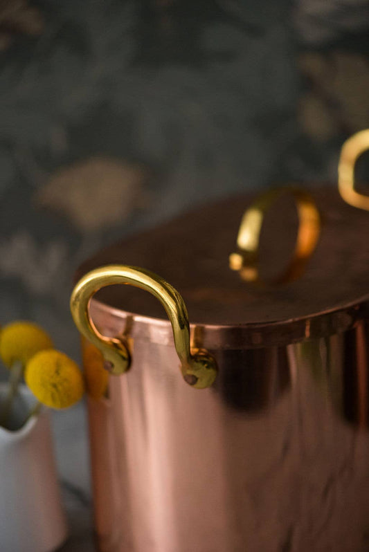 Close-up of the copper bread box's brass side handle and lid