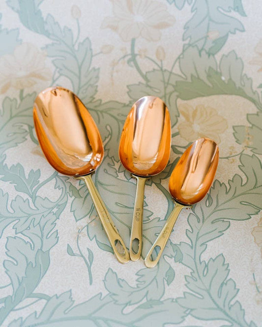 Set of three copper measuring scoops with long handles and oval bowls