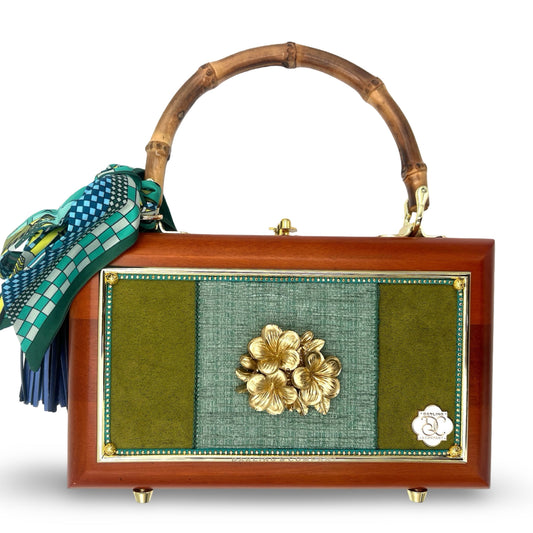 Wooden top-handle handbag with green fabric front panel, gold flower clasp, and scarf bow