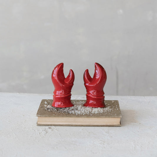 Two red lobster claw salt and pepper shakers on a small wooden base