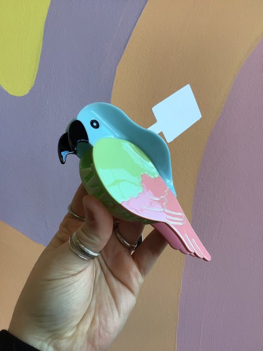 Parrot-shaped hair claw with blue head, mint green wing, and pink tail, glossy