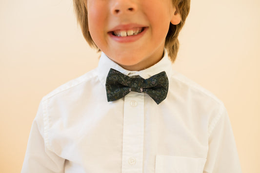 Boys bow tie worn on white shirt front; dark green floral pattern