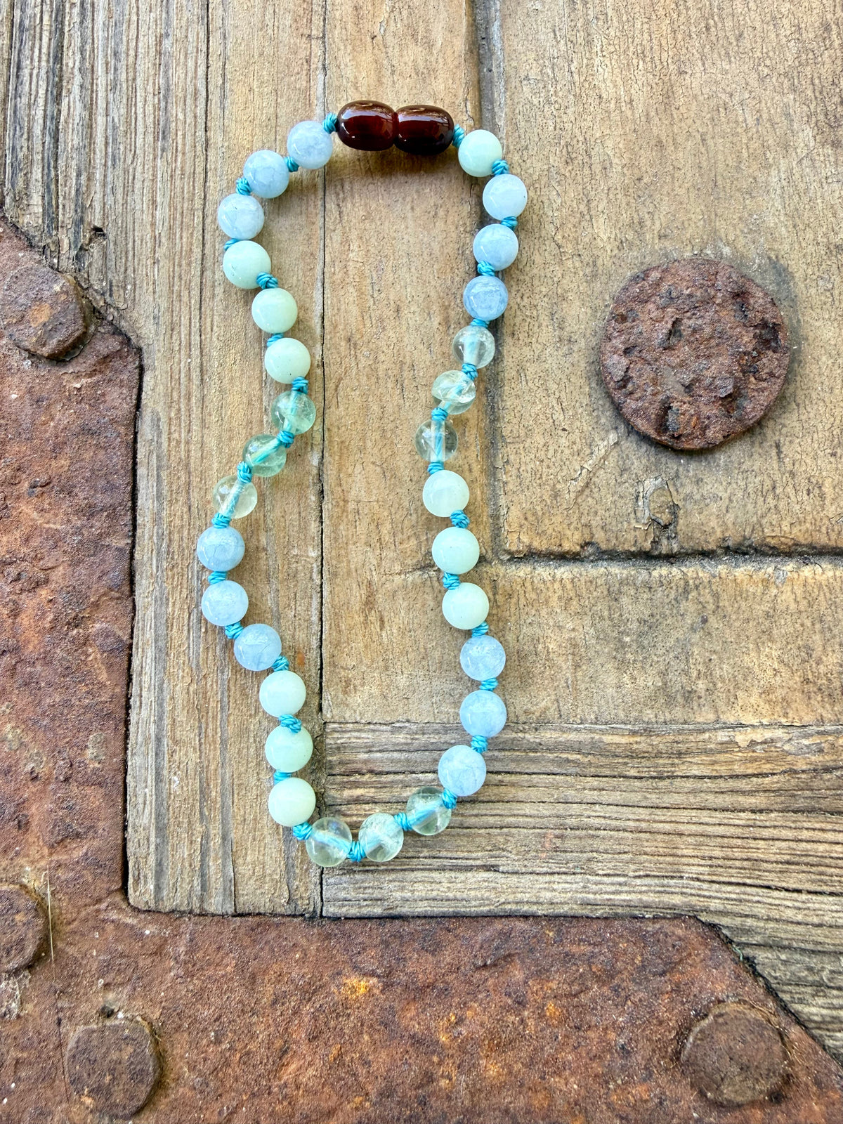 Gemstone bead necklace with light blue beads and teal accents, rounded cabochons