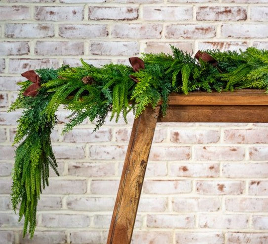 Green faux pine garland with red-brown accents and trailing branches