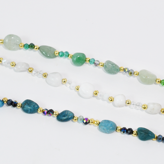Beaded necklace strands in green, white, and blue with gold-tone beads and spacer accents.