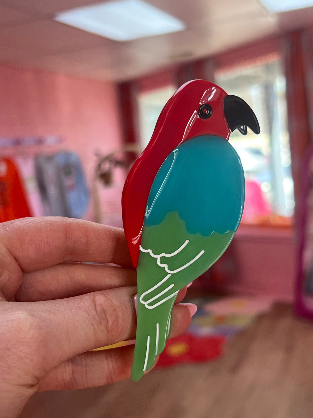 Parrot-shaped hair claw with red head, turquoise wing, and green tail, glossy