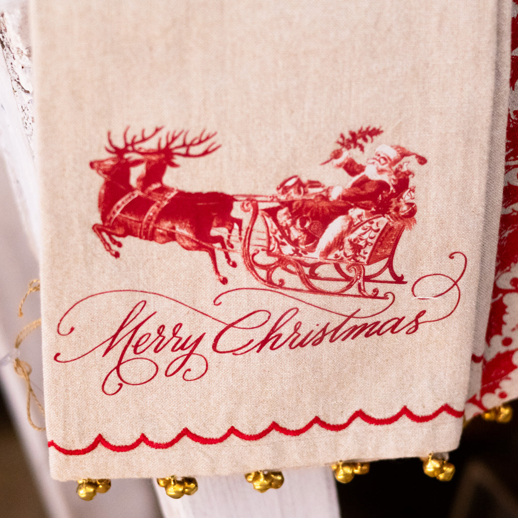 Beige Christmas hand towel close-up with red Santa on sleigh and 'Merry Christmas' lettering
