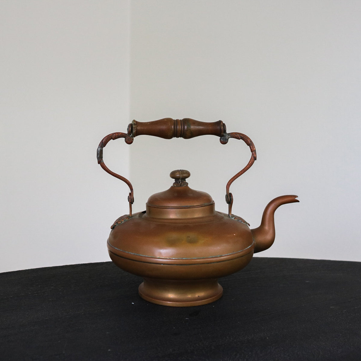 Brass and copper kettle with brown patina, domed lid, and turned wooden-style handles