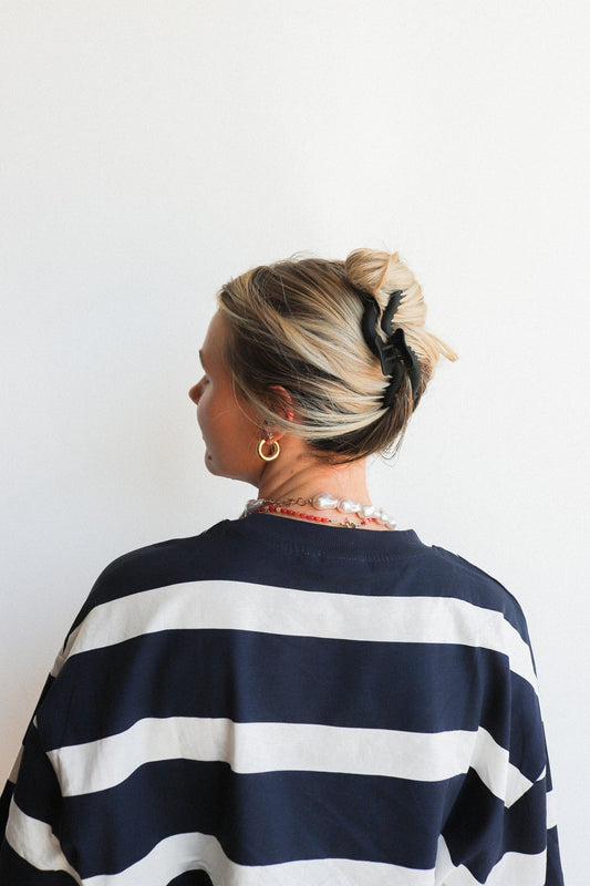 Wavy hair claw clipped in blonde hair bun, black accessory visible