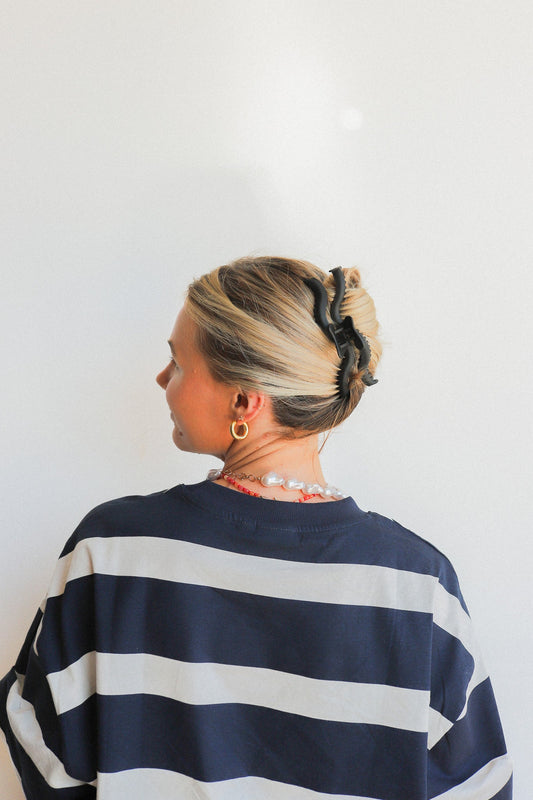 Black wavy claw hair clip holding up a bun