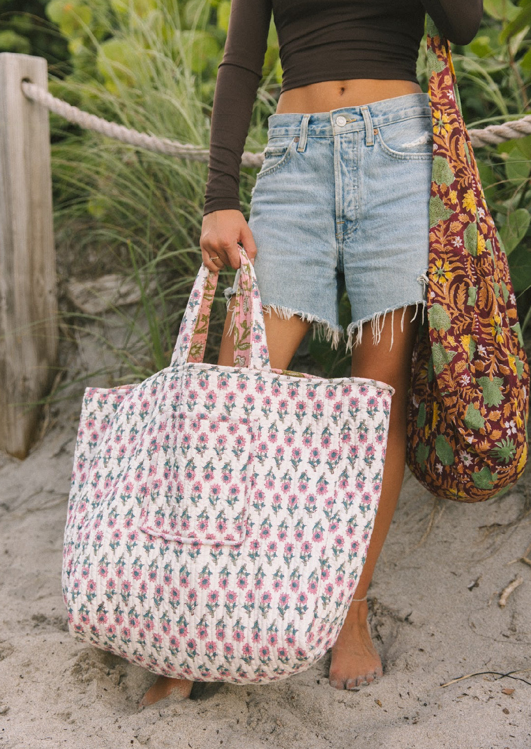 Pink and white floral tote bag with top handles, held while standing