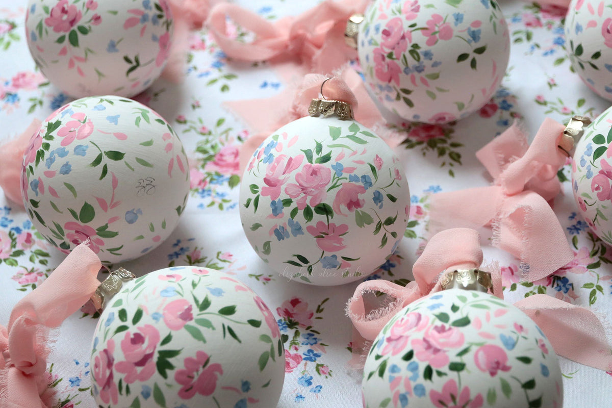 White floral Christmas ornament with hand-painted pink roses and a metal hanging cap