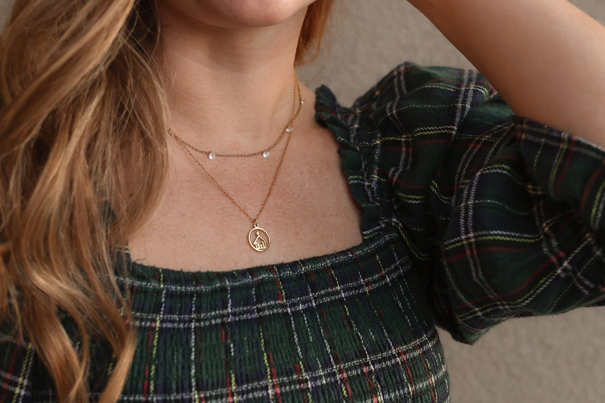 Gold-tone Nativity pendant necklace worn on a fine chain.