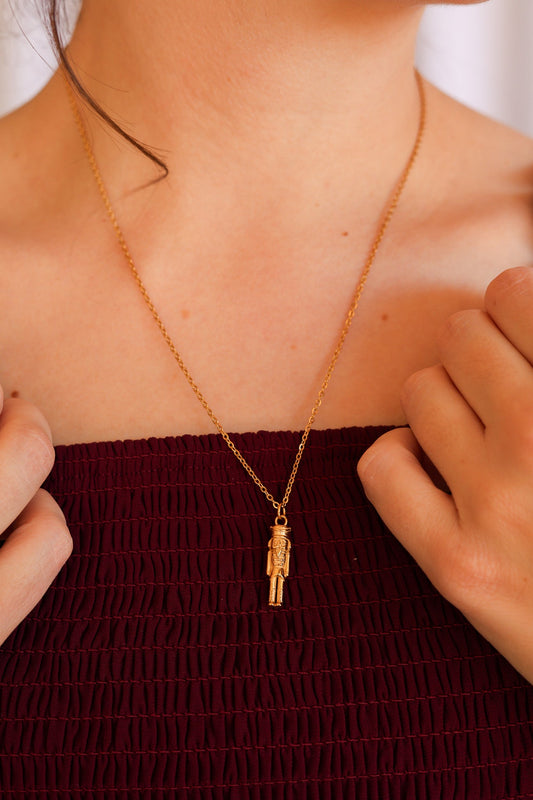 Gold nutcracker necklace worn with its small soldier pendant centered on the chest