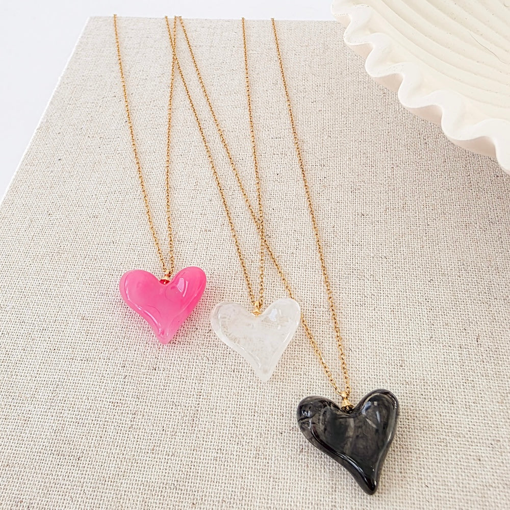 Resin heart necklace set with pink, clear, and black heart pendants on gold chains