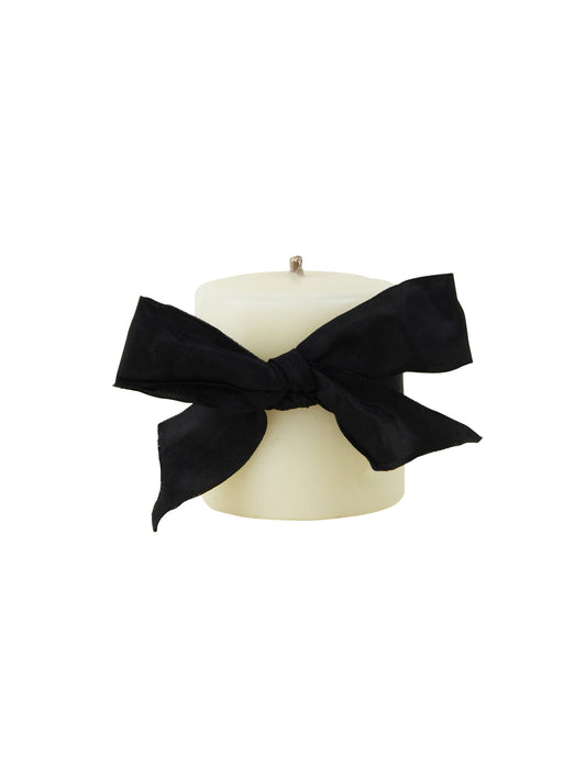 Ivory pillar candle with black bow ribbon on top, smooth beeswax finish