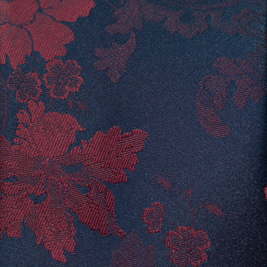 Necktie fabric close-up: dark navy base with merlot red rose floral jacquard.