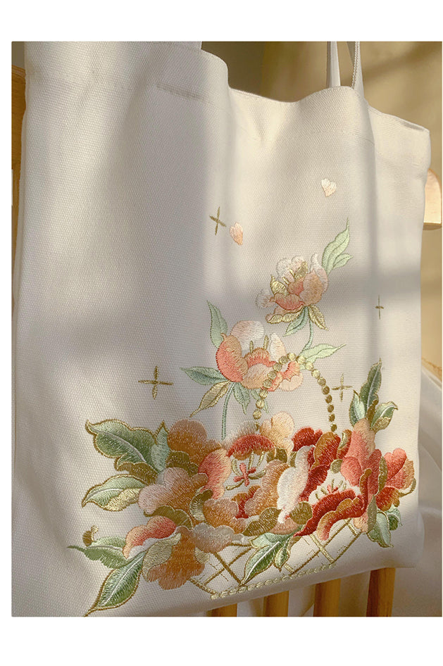 White embroidered tote bag with colorful flower basket motif and small cross accents.