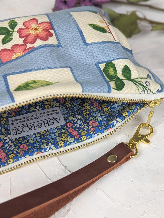 Wristlet purse showing gold zipper pull and floral bird patchwork fabric