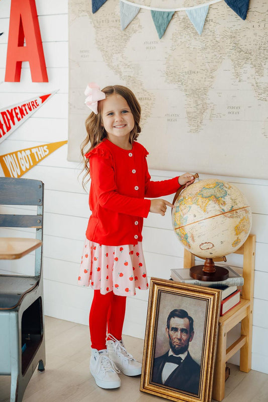 Girl wearing red long-sleeve cardigan with ruffle shoulders and button front