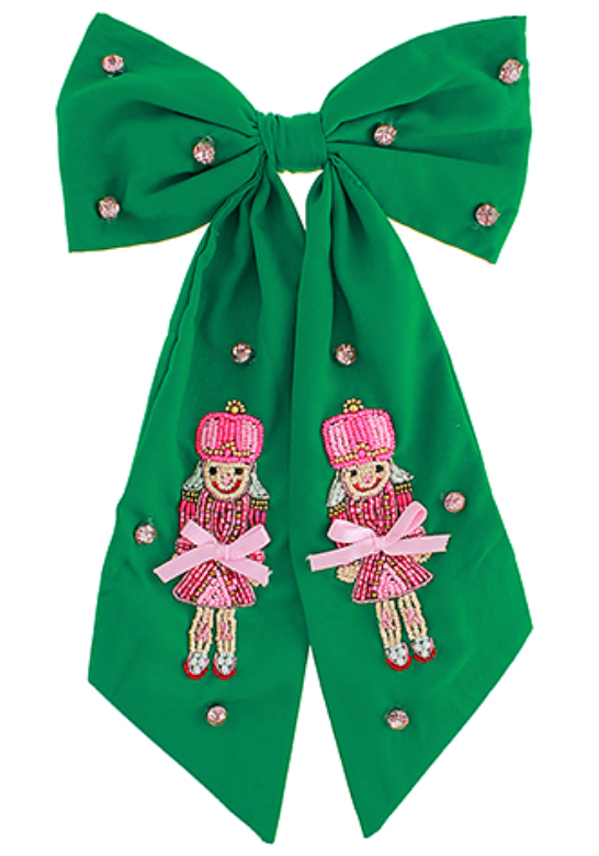 Green fabric bow with long tails, embellished with beads and two pink nutcracker figures
