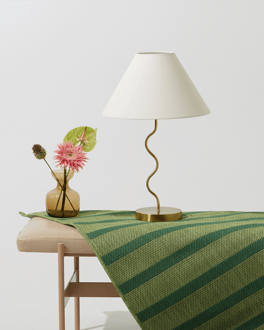 Brass table lamp with off-white fabric shade on round brass base