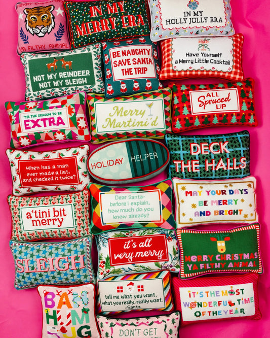 Needlepoint holiday throw pillows with various embroidered text and festive designs