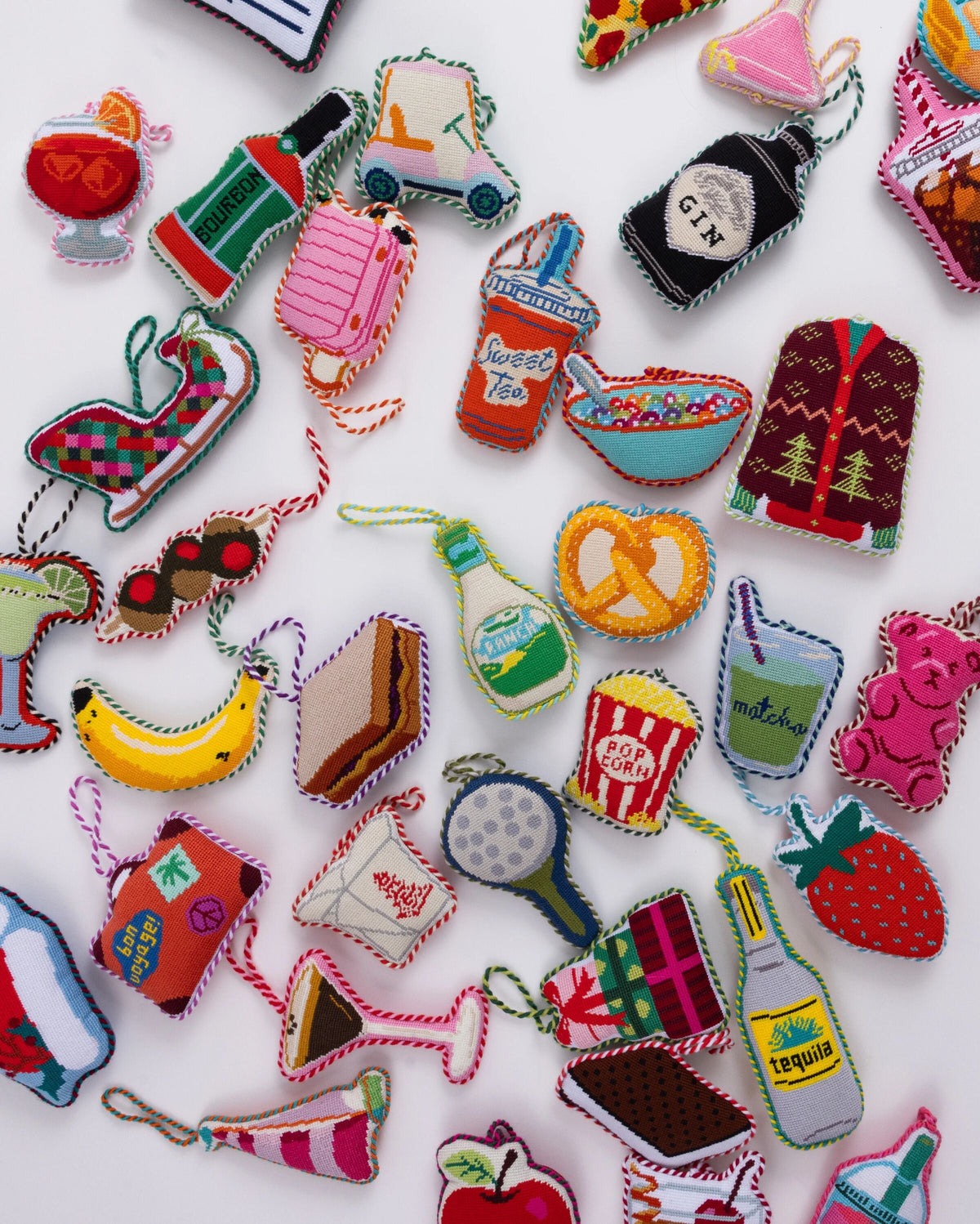 Assorted needlepoint ornaments with colorful stitched designs on white fabric