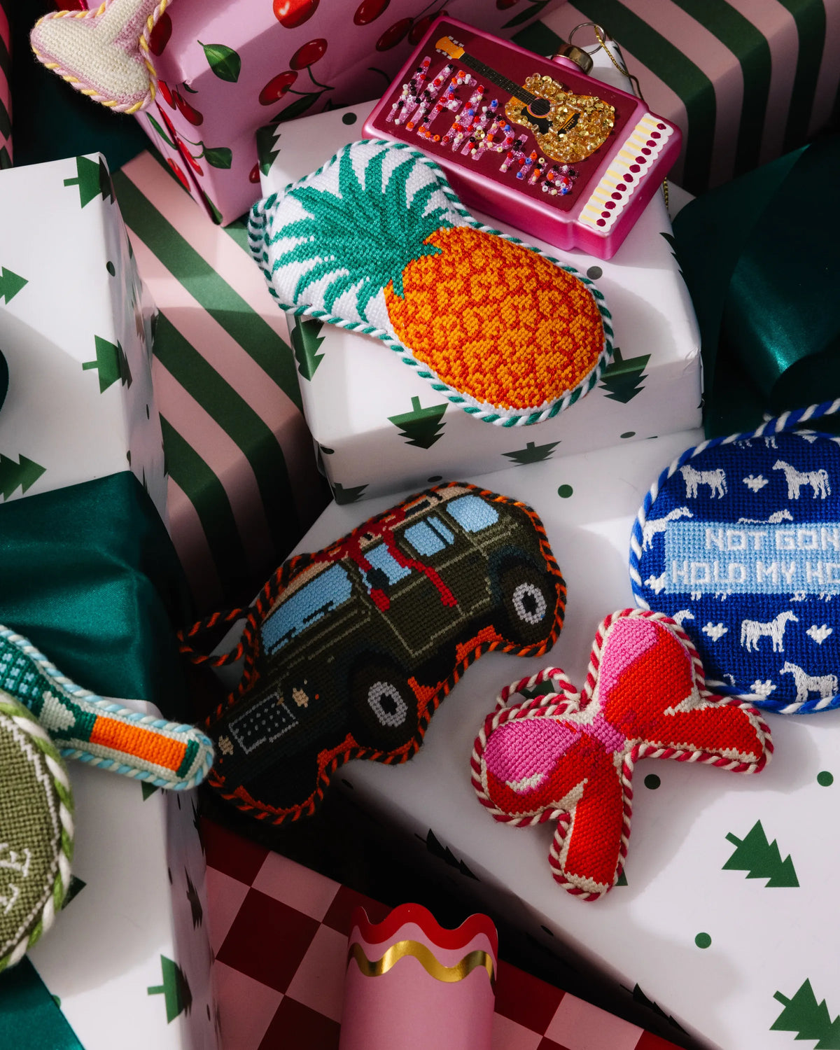 Needlepoint bow ornament resting on wrapped holiday gifts