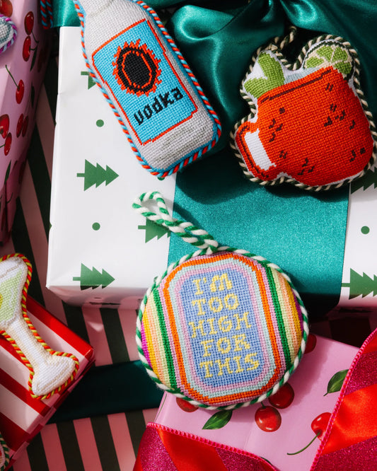 Needlepoint icon ornaments with mixed bottle, drink, and mug designs tied with ribbon