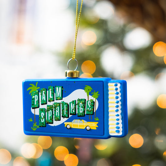 Blue matchbook ornament with gold cap, Palm Springs graphic, hanging loop