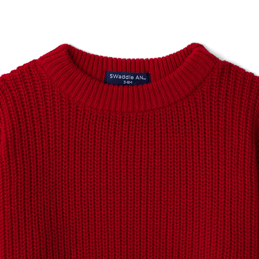 Red knit baby sweater neckline detail with ribbed collar and small brand label at front.