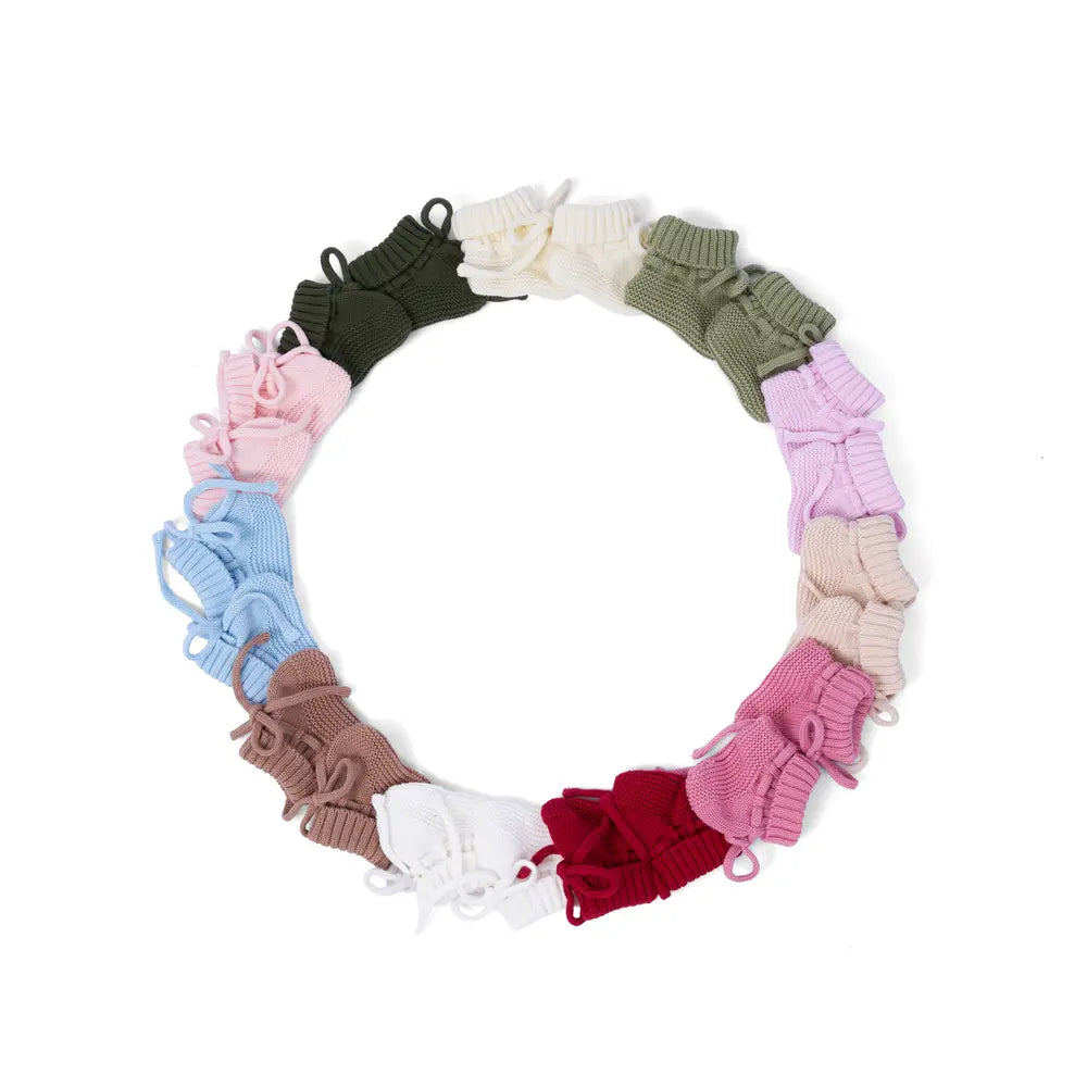 Circular assortment of knitted baby booties in assorted colors, featuring pink